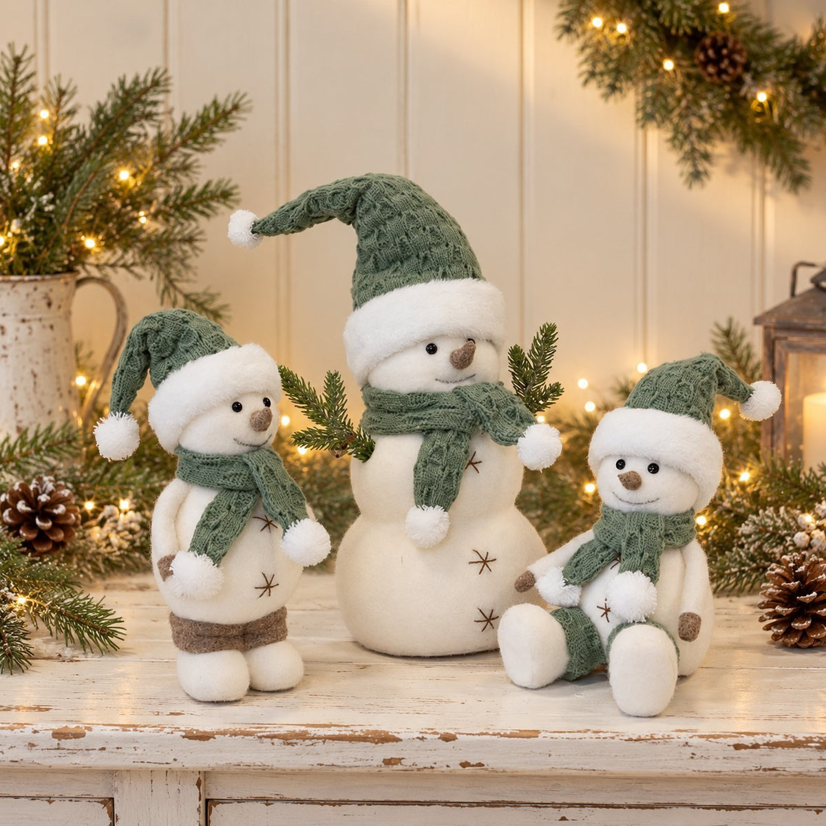 Maison Oie set of three felt snowmen in sage green and white with knitted hats and scarves on a rustic table